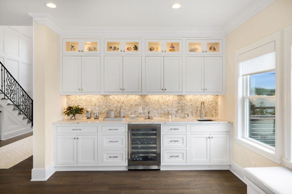 Bright custom kitchen bar with white cabinetry, pearl mosaic backsplash, and built-in wine fridge, styled by a Long Island full-service interior designer specializing in turnkey design.